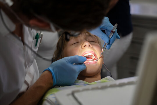 Dentist examining patient's teeth with tools at clinic