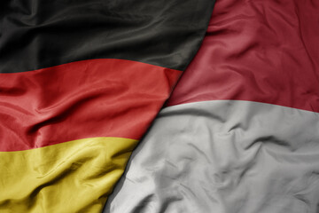 big waving realistic national colorful flag of germany and national flag of indonesia .