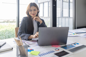 Asian Business woman using calculator and laptop for doing math finance on an office desk, tax, report, accounting, statistics, and analytical research concept
