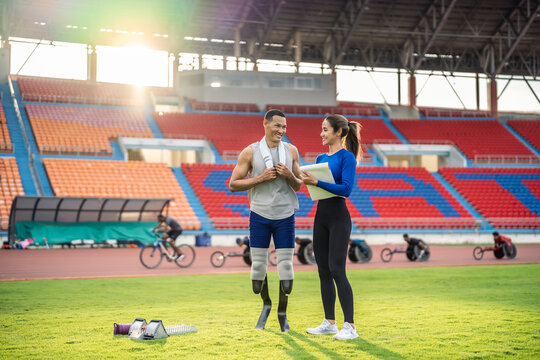 Asian athlete with prosthetic blades and trainer workout in stadium. - Powered by Adobe