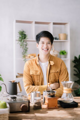 Asian male barista brewing coffee at the kitchen table.