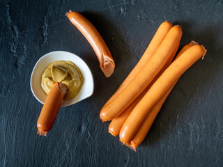 boiled sausages served with mustard on black slate