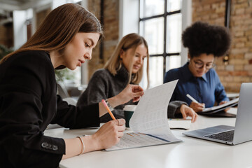 Three young women doing paperwork while sitting in office