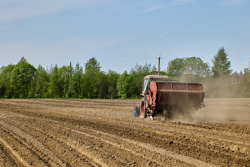 Potato planter is hitched to tractor during planting of potatoes during spring sowing period in...