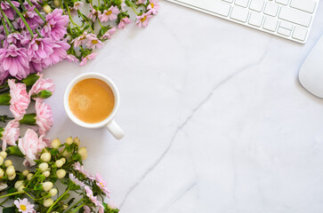 A white cup of hot espresso coffee shot puts on marble working desk with keyboard ,mouse and pink flowers.