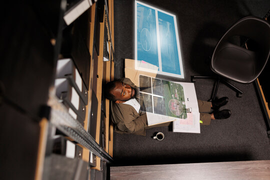 African american man examining augmented reality clues, checking evidence and case files in private investigation space. Male detective trying to solve crime with artificial intelligence hologram.