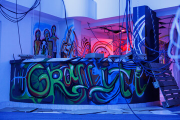 Spray paint on walls glowing with purple neon lights, looking grungy in neglected empty building....