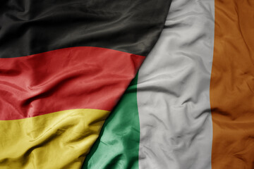 big waving realistic national colorful flag of germany and national flag of ireland .