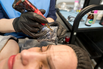  master performs the procedure of permanent eyebrow makeup for the client