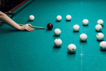 Blond woman playing enjoying billiard, hold cue hit white billiard balls on table with green...