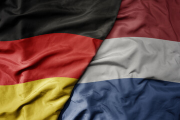 big waving realistic national colorful flag of germany and national flag of netherlands .