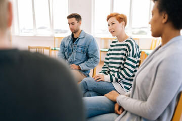 Selective focus of young woman in group psychotherapy session telling about mental problem to other...