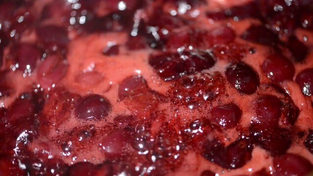 Mixing with a spoon, cooked cherry fruit jam in a pot. Mixing the cherries. 