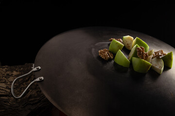 Dark food style capture of mix salad with green apple walnut and cinnamon on aged metal plate