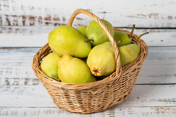 Fresh pears in a wicker basket over wooden background. Pear harvest season concept. Healthy and fresh fruit. Close up
