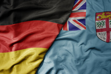 big waving realistic national colorful flag of germany and national flag of Fiji .