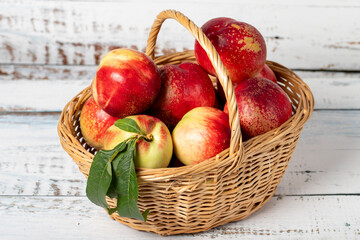 Fresh nectarine in a wicker basket over wooden background. Nectarine harvest season concept. Healthy and fresh fruit. Close up