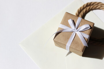 Gift Box Wrapped in Brown Kraft Paper, Decorated with Ribbon Bow, Kraft Envelope, Twine on White. Holidays Gift Packaging Design.