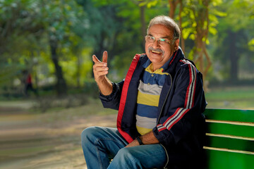 Indian old man laughing and giving expression at park.