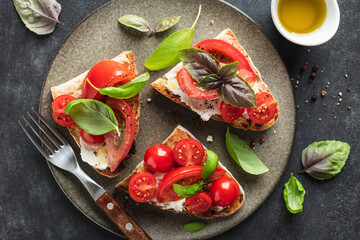 Tomato bruschetta with ricotta cheese and basil garnished with black pepper and olive oil. Top view. Healthy summer snack, wine appetizer