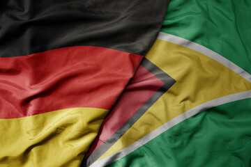 big waving realistic national colorful flag of germany and national flag of guyana .