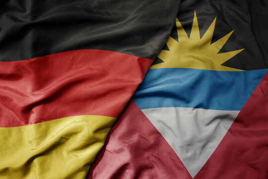 big waving realistic national colorful flag of germany and national flag of antigua and barbuda .