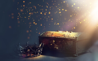 Image of mysterious magical treasure chest with light over wooden old table and dark background