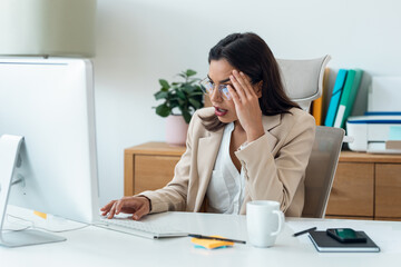 Worried businesswoman working with computer while having problems in the office at home.