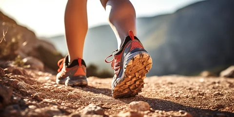 Foto op Plexiglas Bosweg Men's legs with sports shoes and a backpack run along a mountain path.