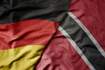 big waving realistic national colorful flag of germany and national flag of trinidad and tobago .