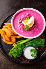 Vegetable cold soup with beet, cucumber, radsih and egg on wooden table