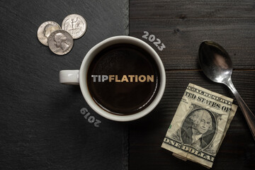 Tipflation (tip creep or tip fatigue) concept: cup of coffee on a table with a dollar and some coins