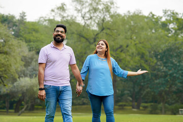Obraz premium young indian couple holding hand each other and walking in park
