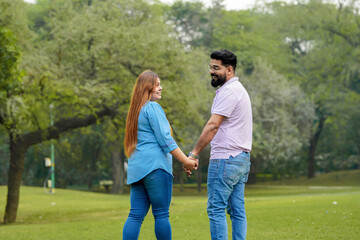 Fototapeta premium young indian couple holding hand each other and walking in park