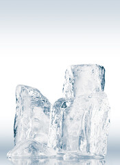 A group of crystal clear crushed ice pieces on a reflective surface isolated on a white.