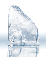 Piece of crystal clear crushed ice block, isolated on a white reflective surface.