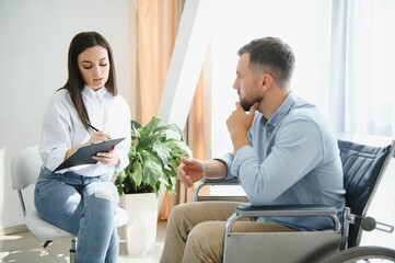 Portrait of female psychiatrist interviewing handicapped man during therapy session, copy space. - obrazy, fototapety, plakaty