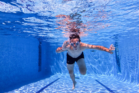 Man with cyberpunk glasses photographed under blue water in a swimming pool