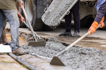 Workers pour the Foundation for the construction of paving a driveway using mobile concrete mixers or concrete mixer truck. Spreading concrete for sidewalk repair - obrazy, fototapety, plakaty