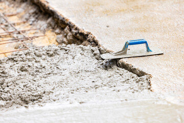 Pouring cement concrete casting on reinforcing metal bars of sidewalk and Metallic Trowel for...