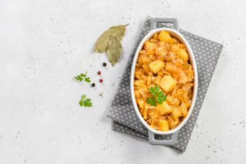 Spicy stewed cabbage potato in ceramic baking dish. Top view, copy space, flat lay.