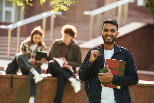Positive Indian man. Young students in casual clothes are together outdoors