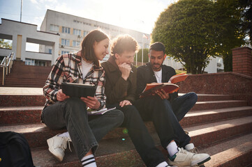 University building is behind. Young students in casual clothes are together outdoors
