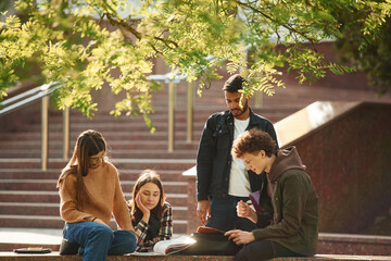 Hanging out after lessons. Four young students in casual clothes are together outdoors