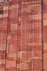 Ancient red sandstone Qutub Minar fresco and motifs on tower wall. Wall Detail from Qutub Minar monument Ancient carved red sandstone buildings at in Delhi, India. UNESCO World Heritage Site