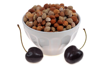Noyaux de cerises dans un bol avec deux cerises en gros plan sur fond blanc