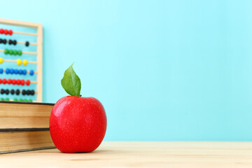 education and back to school concept. apple, abacus, books over wooden desk infront of pastel blackboard