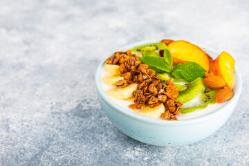 Bowl of granola with yogurt and fresh berries on a texture table. Yogurt berries, acai bowl, spirulina bowl. Healthy food, balanced breakfast. Strawberries, blueberries, kiwi, peach, almonds and chia.