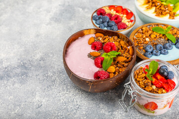 Bowl of granola with yogurt and fresh berries on a texture table. Yogurt berries, acai bowl, spirulina bowl. Healthy food, balanced breakfast. Strawberries, blueberries, kiwi, peach, almonds and chia.