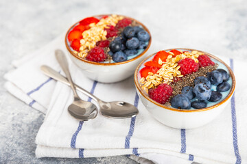 Bowl of granola with yogurt and fresh berries on a texture table. Yogurt berries, acai bowl, spirulina bowl. Healthy food, balanced breakfast. Strawberries, blueberries, kiwi, peach, almonds and chia.